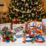 Best Christmas gifts for 5 year old boys including a scooter, magnetic tiles, a snap circuits kit, a race track, and an art case arranged in front of a decorated Christmas tree