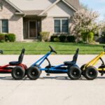 Best pedal go kart for kids showing three colorful karts in red, blue, and yellow lined up on a residential driveway
