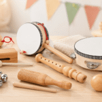 Stoie's Wooden Music Set arranged on a light wooden table with a tambourine, drum, recorder, bells, maraca, tone block, and other wooden musical instruments.