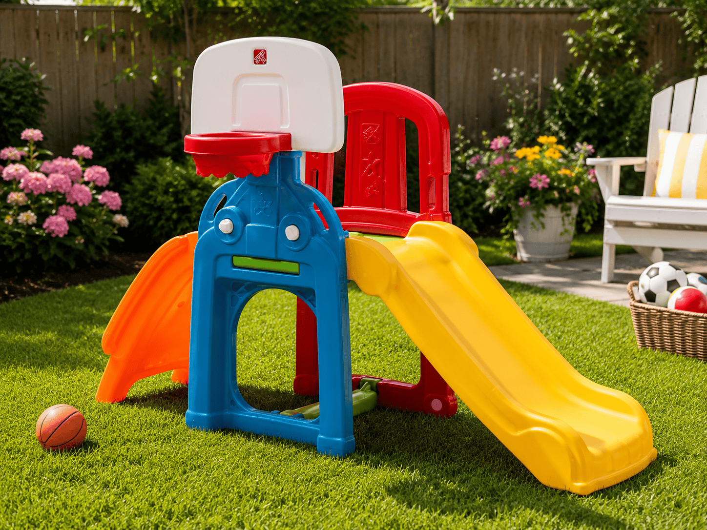 Step2 Game Time Sports Climber set up in a sunny backyard with a slide, basketball hoop, green grass, and colorful outdoor play area