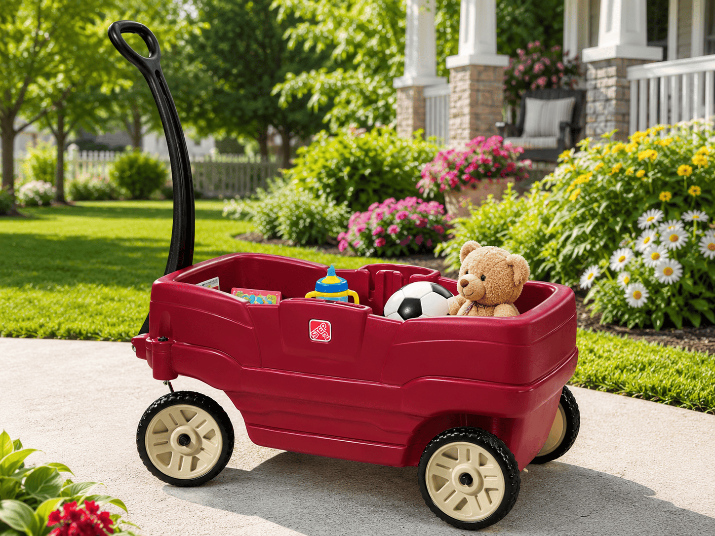 Step2 Neighborhood Wagon in a sunny backyard garden with toys inside, green grass, flowers, and a bright outdoor setting