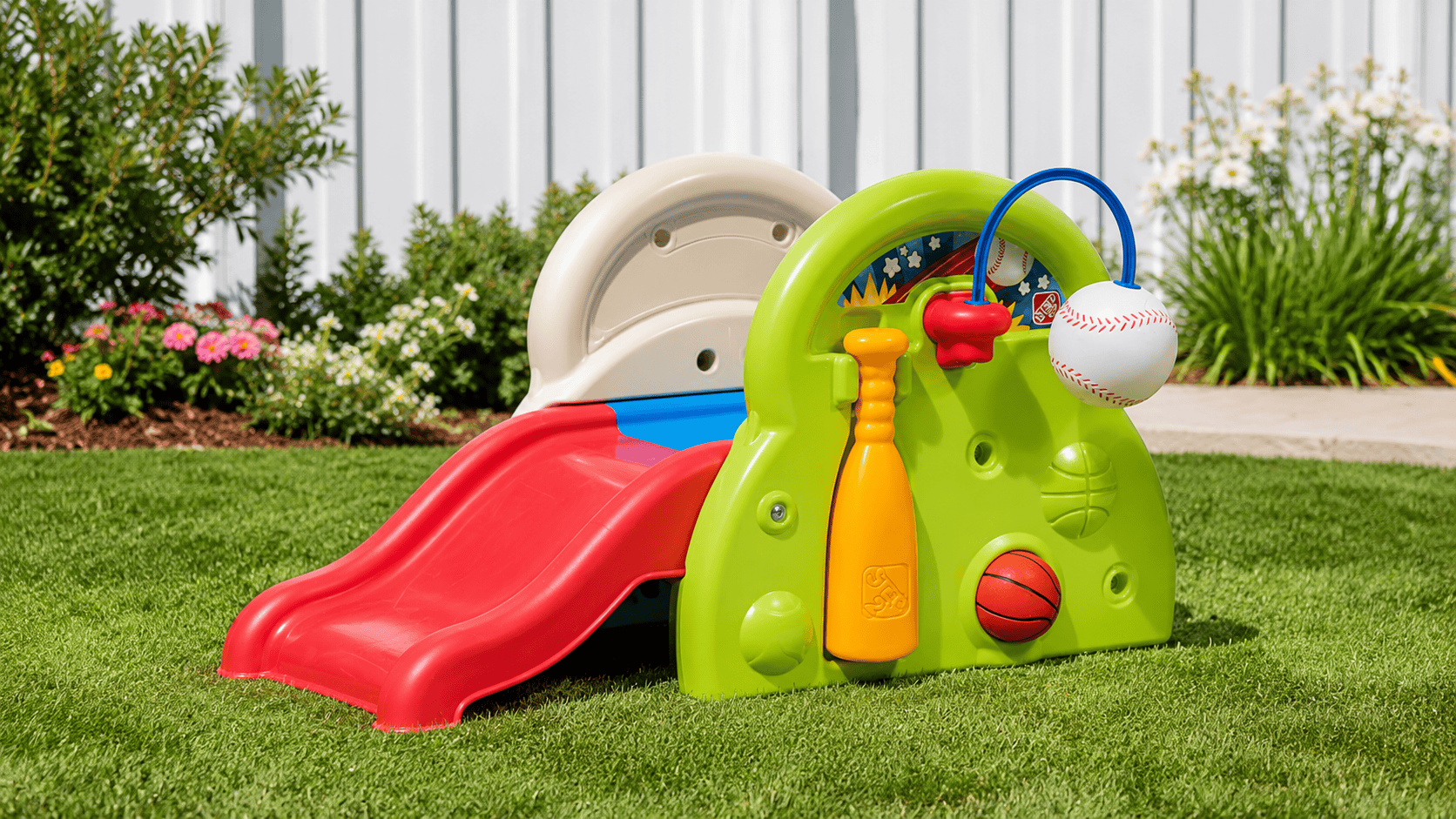 Step2 Sports-Tastic Activity Center set up in a sunny backyard with slide, baseball, basketball, and colorful sports play features