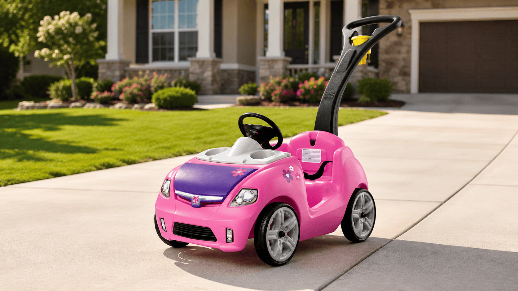 Step2 Whisper Ride II Kids Push Car parked in a sunny driveway in a beautiful neighborhood with a manicured lawn and house in the background